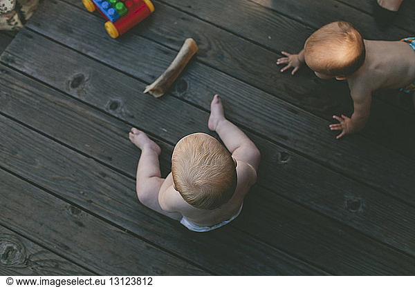 High angle view of shirtless baby girls on floorboard at birthday party