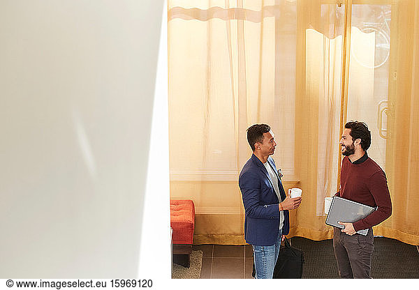 High angle view of smiling businessmen discussing while standing at workplace