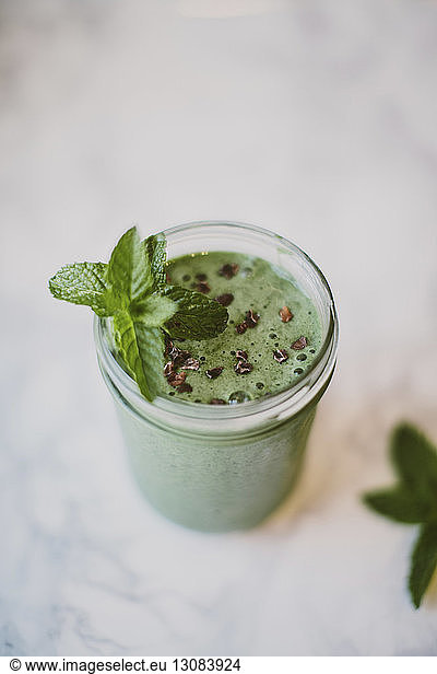 High angle view of smoothie with mint leaves and cacao nibs in mason jar on table