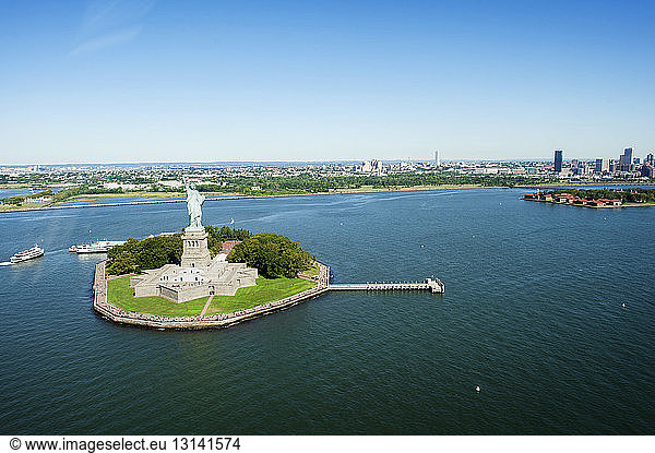 High angle view of Statue of Liberty on island amidst sea against blue sky