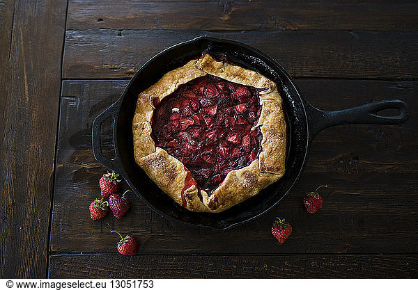 High angle view of strawberry pie in skillet on wooden table