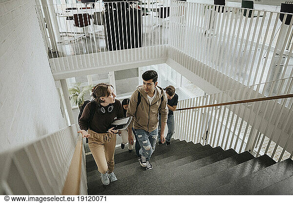 High angle view of students talking while moving up on steps in university