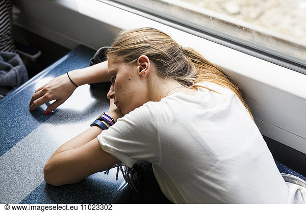 High angle view of tired businesswoman sleeping on table in train