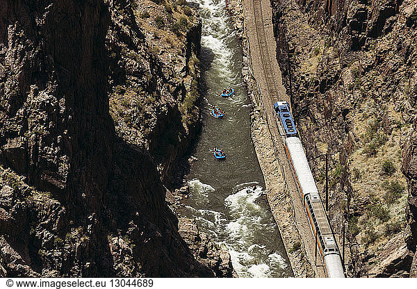 High angle view of tourists rafting on river amidst rock formations and train