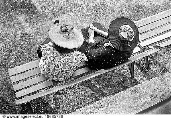 High angle view of two women wearing print dresses and large straw hats  sitting on park bench  Washington  D.C.  USA  David Myers  U.S. Farm Security Administration  1939