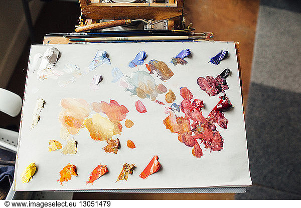 High angle view of watercolor paints on paper at table in workshop