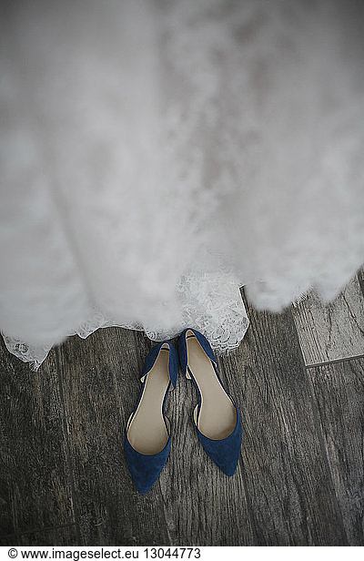 High angle view of wedding dress and sandals on hardwood floor at wedding ceremony