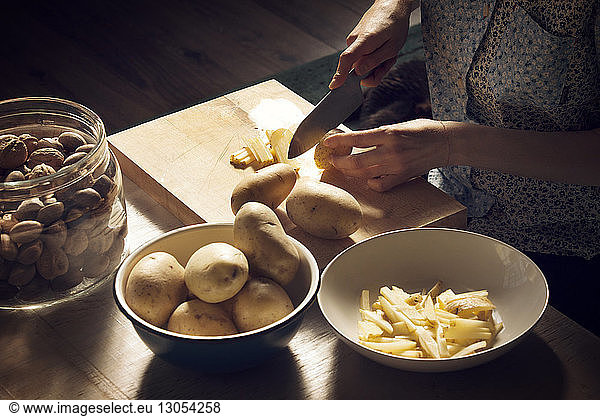 High angle view of woman cutting potatoes on cutting board at home