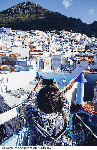 High angle view of woman photographing townscape through mobile phone