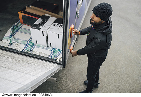 High angle view of worker opening van trunk by pushing buttons on street