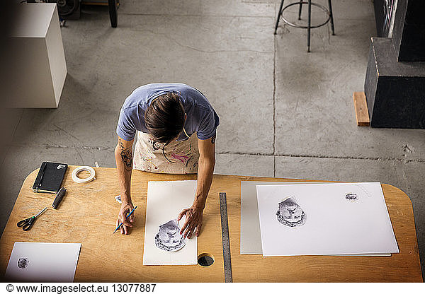 High angle view of worker sketching while working in workshop