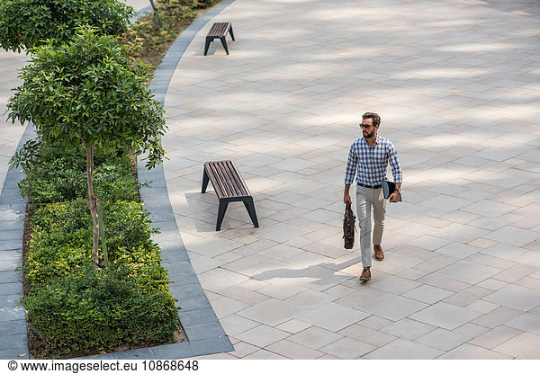 High angle view of young man walking in city carrying digital tablet  Dubai  United Arab Emirates