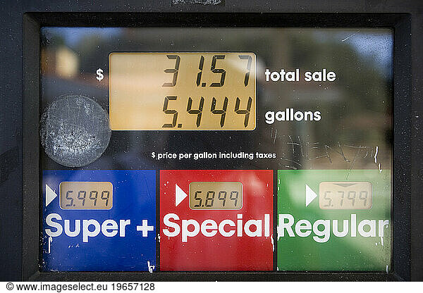 High gas prices reflected in sign at a gas station as drivers fill up their vehicle.