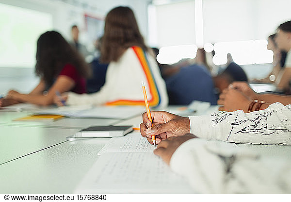 High school student studying  writing in notebook during lesson in classroom