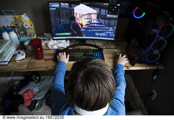 High View of Teen Boy Playing on Gaming Computer at Messy Desk