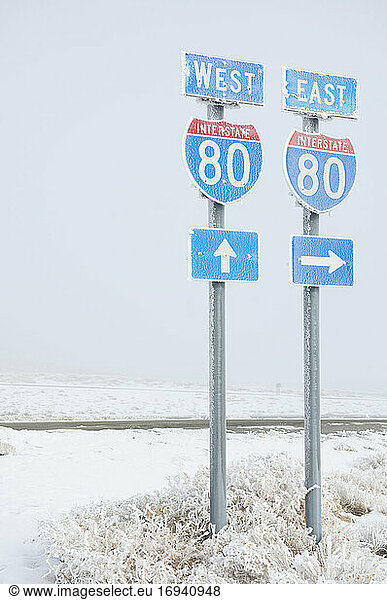 Highway signs on road in wintry snowy landscape.