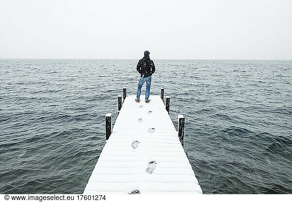 Hiker admiring lake standing on snow covered jetty in winter  Walchensee  Bavaria  Germany
