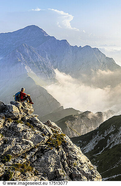 Hiker admiring view while sitting on mountain peak at Bergamasque Alps  Italy