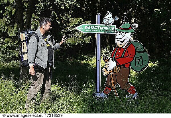 Hiker and sign Wetzsteinhütte  man with backpack in front of signpost at Altvaterturm on Wetzstein  memorial against the expulsion of people  Rennsteig  high-altitude hiking trail  Thuringian Forest  Green Belt  border trail  former German-German border