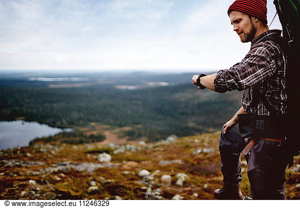 Hiker checking time on cliff top  Keimiotunturi  Lapland  Finland