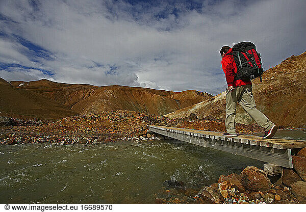Hiker crossing wooden bridge in the Icelandic highlands