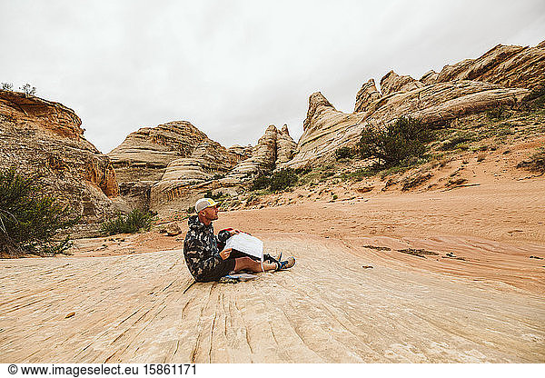hiker in camo jacket checks his map in a desert arroyo basin