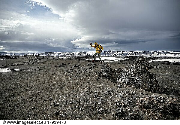 Hiker jumps into the air  snow-covered volcanic landscape with volcanic sand and petrified lava  crater of Askja volcano  Icelandic highlands  Iceland  Europe