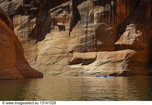 Hiker kayaking on Lake Powell against canyons