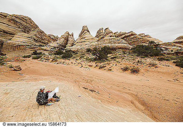 hiker looks at The Fins and checks his map on a hike in the canyonland