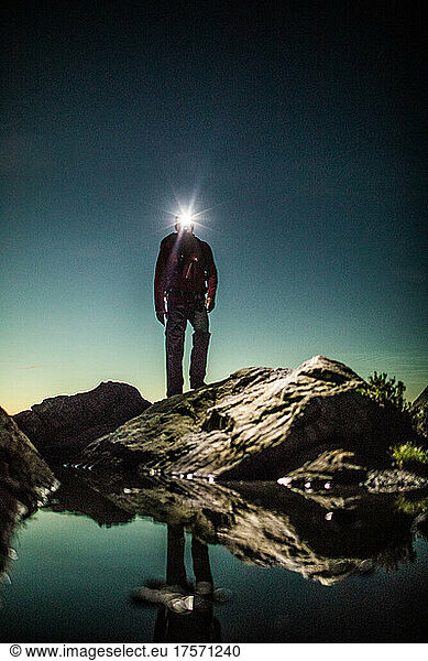 Hiker navigating rocky terrain at night using headlamp.