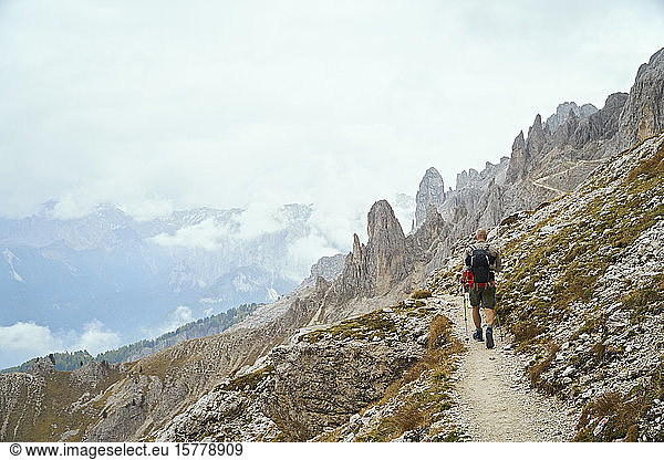 Hiker on dirt track on mountain side  Canazei  Trentino-Alto Adige  Italy
