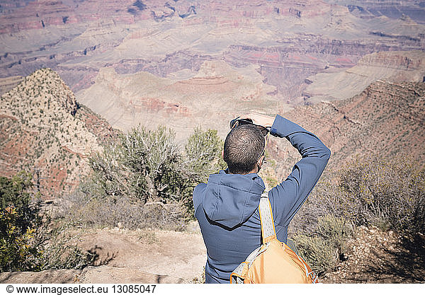 Hiker photographing against mountains