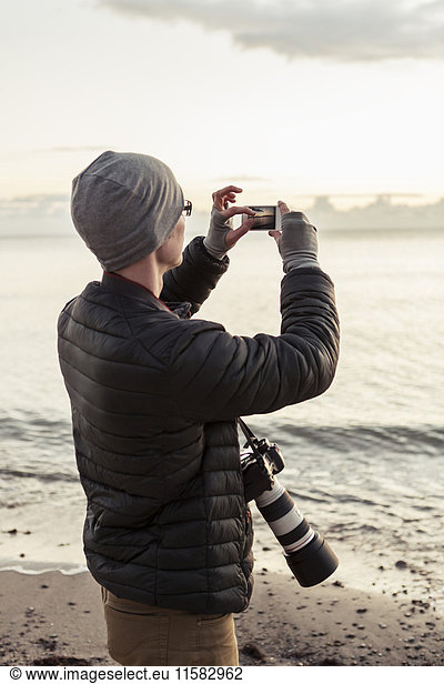 Hiker photographing through smart phone at beach