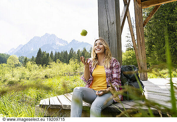 Hiker playing with apple relaxing on wooden boardwalk at Zelenci Nature Reserve