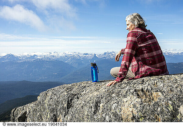 Hiker resting and looking at view while sitting at top of Whistler Mountain  Garibaldi Provincial Park  Whistler  British Columbia  Canada