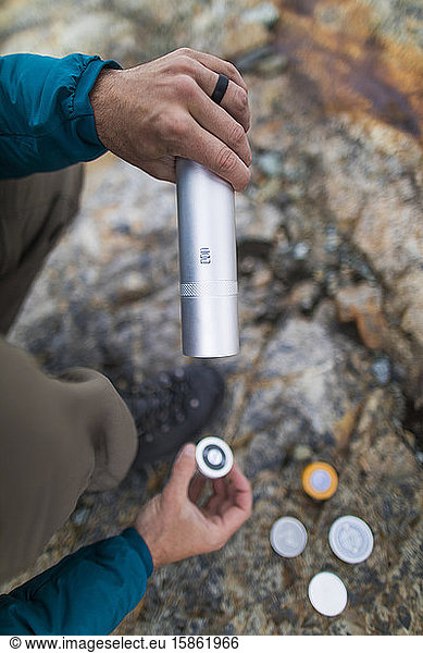 hiker searches for survival supplies in organized gear tube.