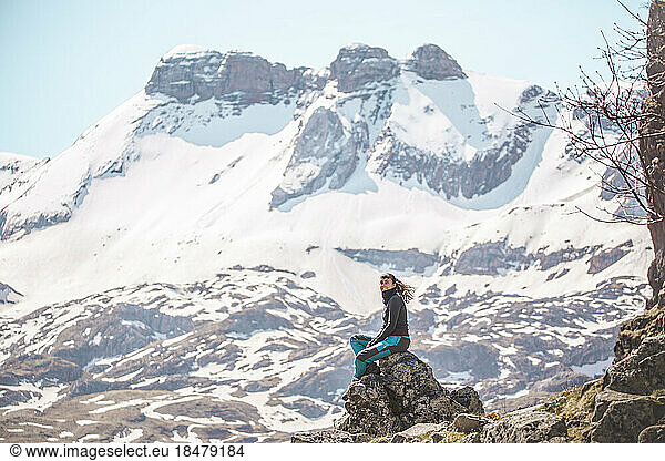 Hiker sitting on rock in front of snowy mountains