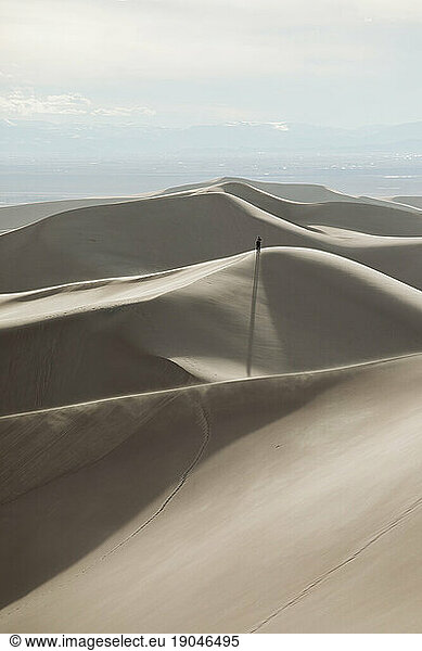 hiker stands on top of a distant ridge at great sand dunes park
