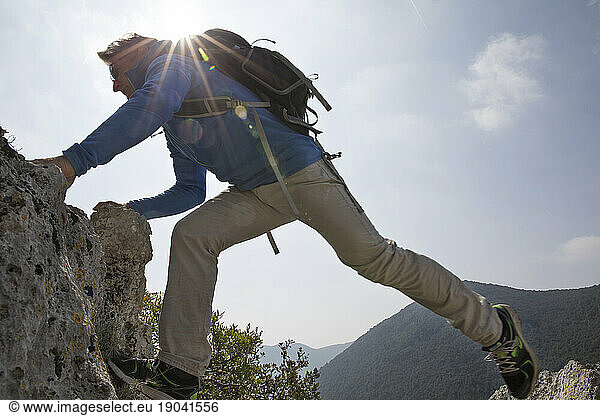 Hiker stretches across rock gap in mountains