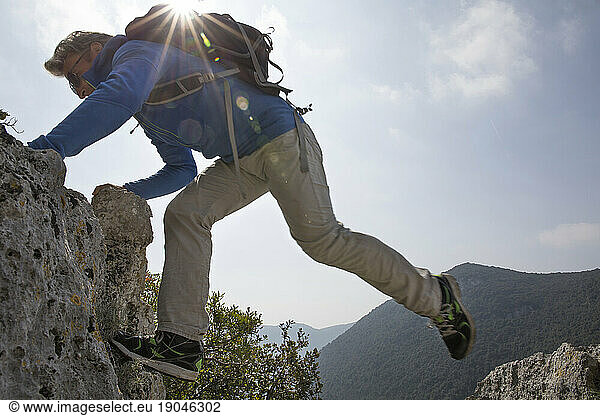 Hiker stretches across rock gap in mountains