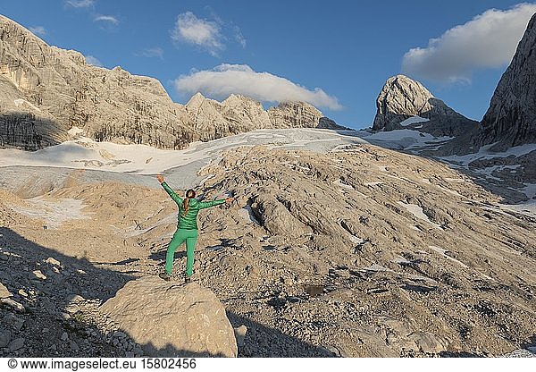 Hiker stretches arms in the air  Alpine landscape  Great Gosau Glacier  Hohes Kreuz  Hoher and Niederer Dachstein  Salzkammergut  Upper Austria  Austria  Europe