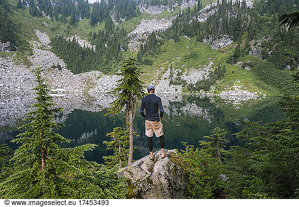 Hiker taking in the serene views of an alpine lake in washington