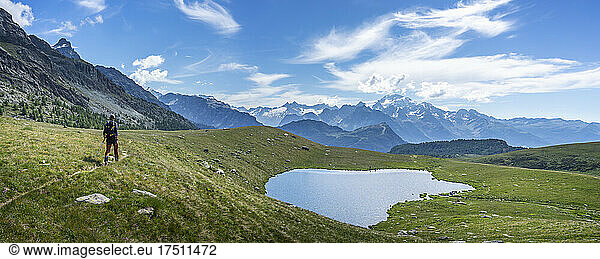 Hiker walking near lake on mountain at Western Rhaetian Alps  Sondrio  Italy