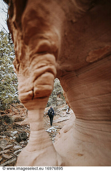 hiker walks down canyon near arch in Grand Staircase Monument  Utah