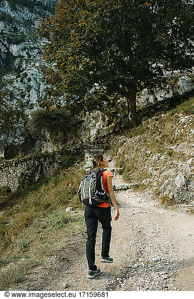 Hiker wearing backpack looking away while walking on Cares Trail at Picos De Europe National Park  Asturias  Spain