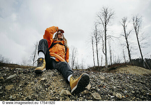 Hiker wearing orange jacket shielding eyes