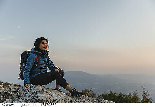 Hiker with backpack contemplating on rock