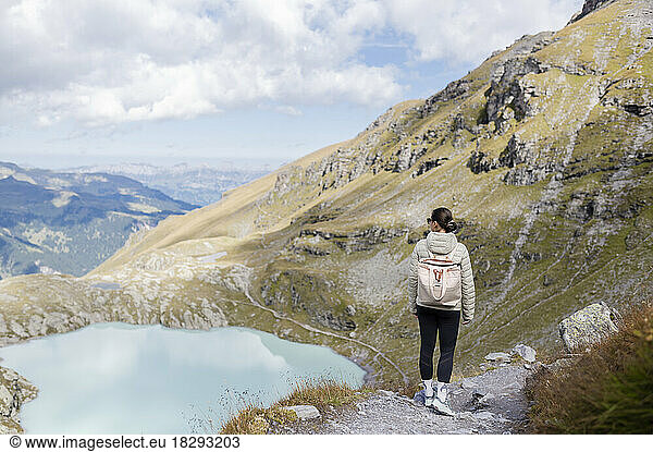 Hiker with backpack standing on rock looking at mountain