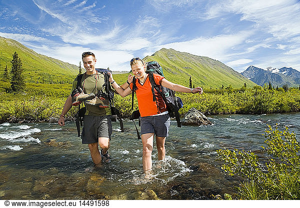 Hikers in Chugach State Park crossing South Fork of Eagle River using correct fording techniques Alaska