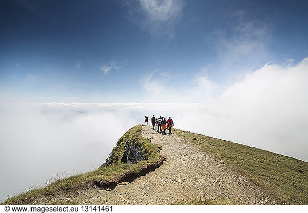 Hikers on cliff covered by clouds